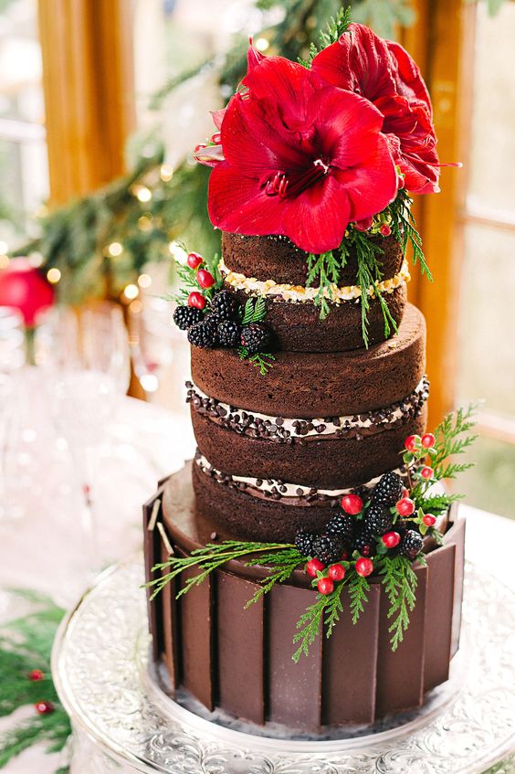 a chocolate Christmas cake with naked tiers, fresh berries, greenery and bold red poinsettias on top is a lovely idea