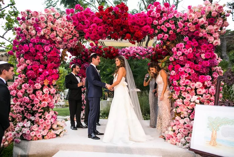 A lush and bold wedding arch covered with pink, hot pink and fuchsia blooms is a fantastic decor idea for a bold wedding