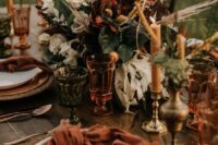 36 a bright mid-Western wedding table setting with dark blooms and greenery, colored glasses and amber candles, rust and orange touches