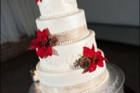36 a classic winter wedding cake in white, with sugar patterns, beads, red poinsettias, pinecones, berries and evergreens