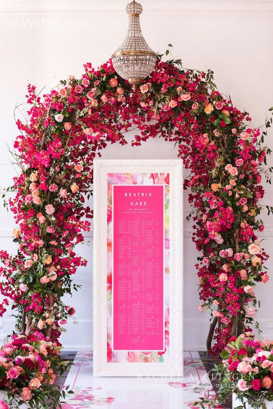 a lush and colorful wedding arch with pink, hot pink and fuchsia blooms plus greenery is wow