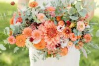 38 a bold summer wedding bouquet composed of orange and pink dahlias, pink ranunculus, smaller fillers and greenery