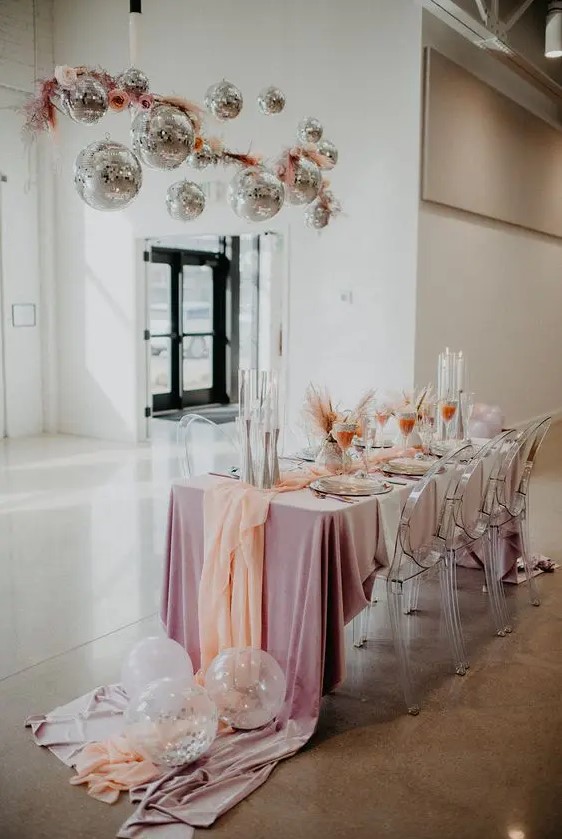 a glam party chandelier of pink pampas grass, blooms and disco balls for decorating your wedding reception space