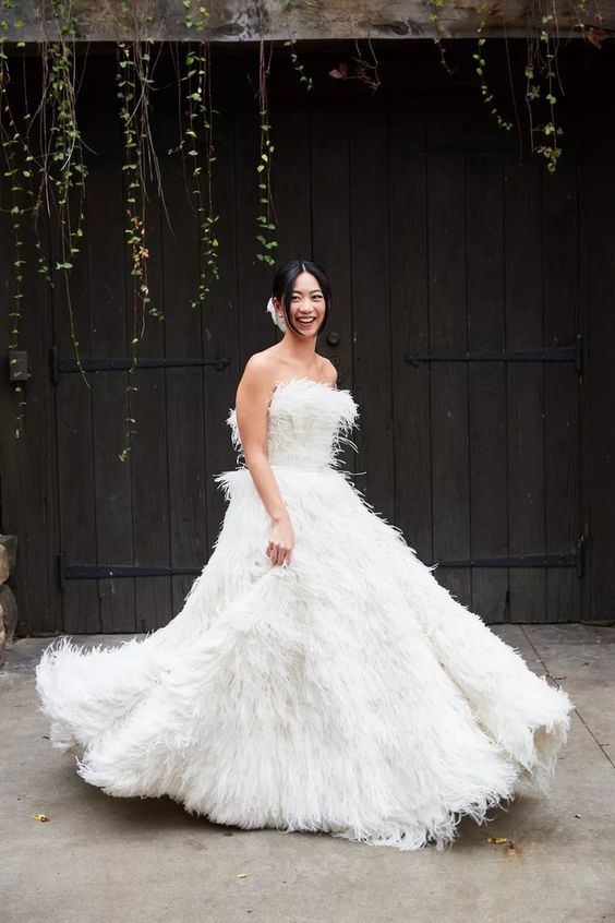 a feather strapless wedding ballgown with a train is a fantastic and extra bold solution for a modern and refined bride