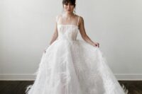 41 a modern wedding ballgown with spaghetti straps and a full skirt with a train and feathers on it