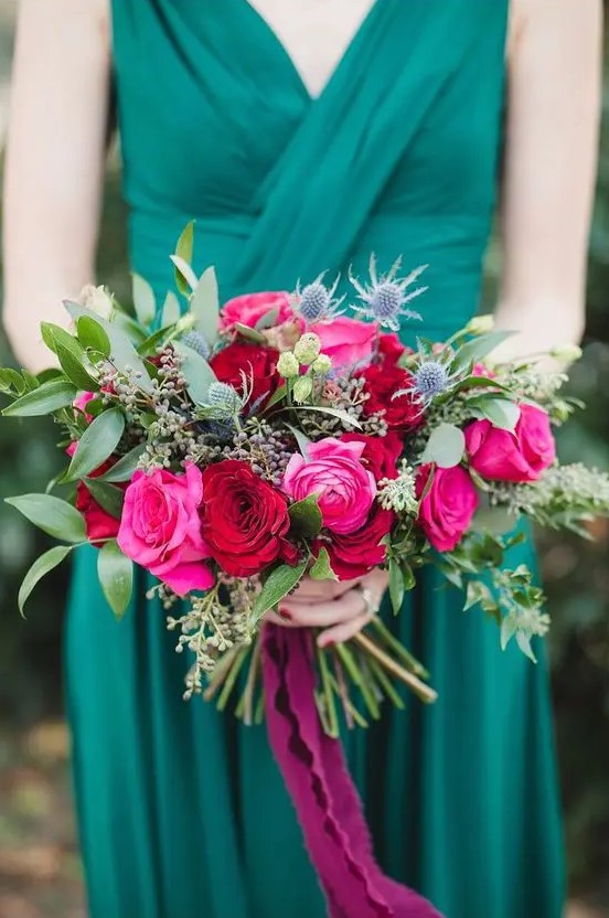 an emerald draped bridesmaid dress and a jewel-tone bouquet with magenta, red blooms, greenery and thistles for a colorful fall wedding