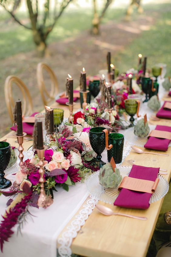 an exquisite wedding tablescape with neutral and magenta blooms, black candles, greenery glasses and magenta napkins is amazing for woodland locations