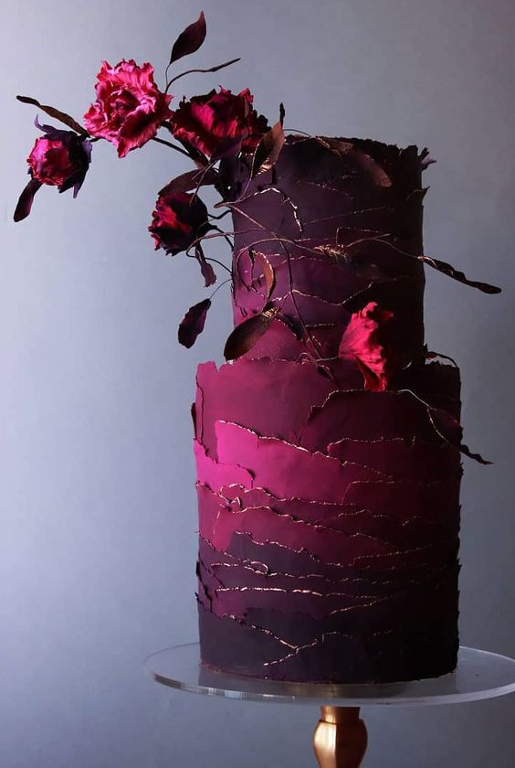 a jaw-dropping wedding cake with magenta, burgundy and deep purple tiers and gold edges plus some matching blooms