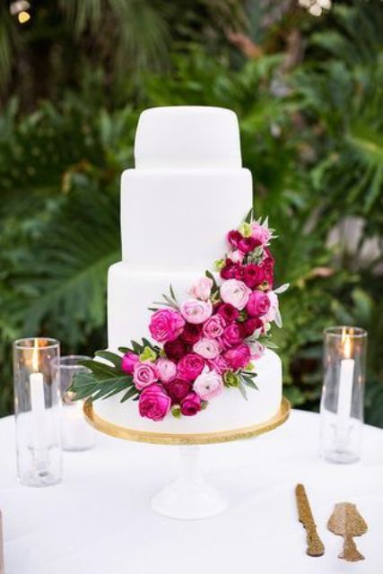 a white wedding cake decorated with light, hot pink and fuchsia blooms plus some leaves is a stylish idea for a tropical wedding