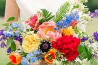 47 a colorful wedding bouquet with red, blush, yellow, orange, blue and purple blooms, greenery and fern for summer