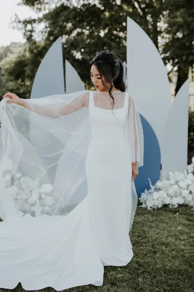 a minimalist sheath wedding dress with thick straps and a pearl capelet that makes the bridal look more girlish and glam
