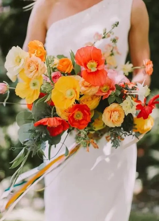 a fantastic colorful wedding bouquet of white, peachy, yellow, red poppies and greenery and long ribbon is amazing for summer