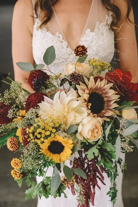 a sumptuous fall wedding bouquet of burgundy and neutral dahlias, peony roses, sunflowers, greenery and dark foliage