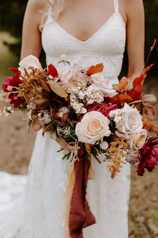 a vibrant fall wedding bouquet of fuchsia, blush, rust blooms, berries, dark foliage and matching ribbons is great for a boho wedding