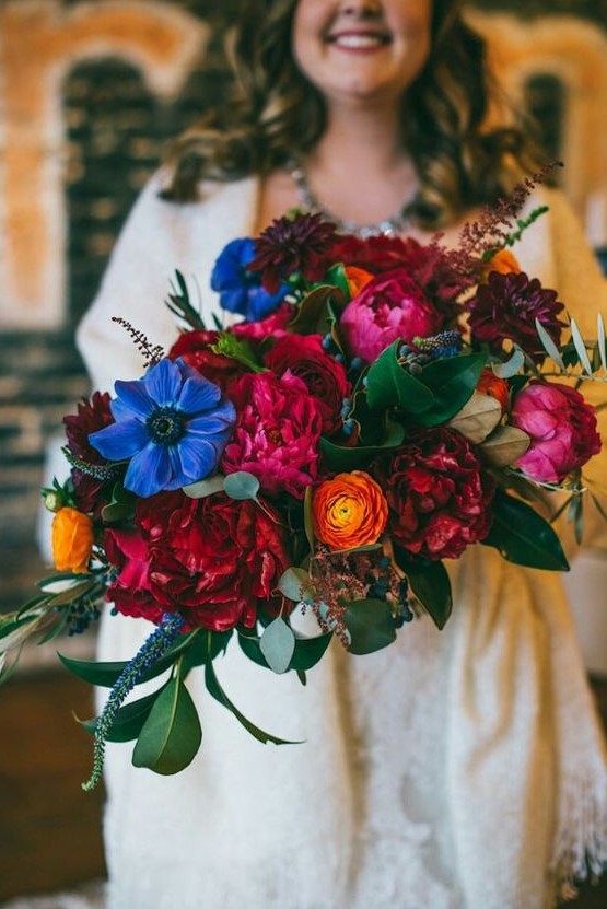 a bold wedding bouquet with fuchsia, red, blue, yellow flowers, privet berries and foliage for a bright fall wedding