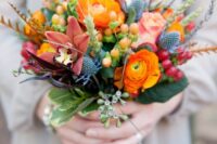 60 a bright and cool fall wedding bouquet with orange ranunculus, roses, orchids, berries, thistles and greenery