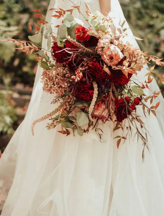 a vibrant fall wedding bouquet of pink and burgundy blooms, greenery and bold fall foliage, grasses and dried blooms is amazing