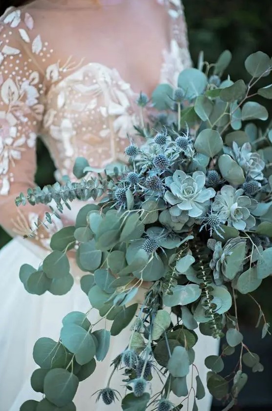 a pale green cascading wedding bouquet with eucalyptus, succulents and blue thistles for a fairy-tale feel