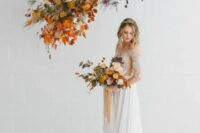 a beautiful and chic floral on air wedding altar with orange and yellow blooms, greenery, dark foliage and twigs, pampas grass