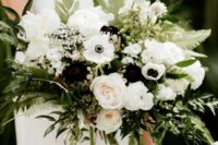 a beautiful and lush wedding bouquet of white anemones and peony roses, ranunculus, dark dahlias and lots of greenery