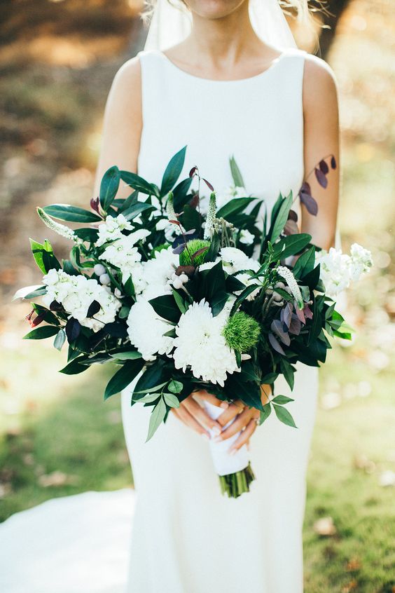 a beautiful modern wedding bouquet of white dahlias, berries, astilbe, black and green foliage is amazing