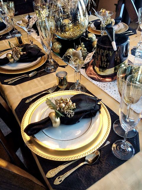 a black and gold wedding tablescape with black placemats, napkins, a top hat and a whimsical centerpiece in black and gold