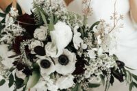 a black and white textural wedding bouquet of white roses and ranunculus, dark blooms and white anemones plus greenery and twigs