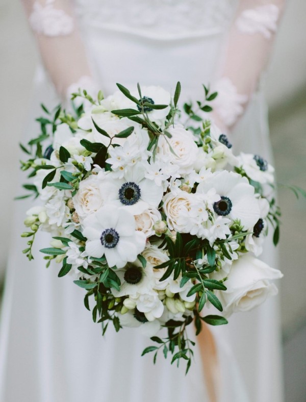 a black and white wedding bouquet of white anemones, roses and smaller blooms, greenery and dark accents