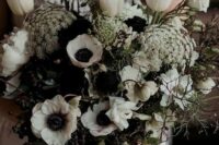 a black and white wedding bouquet that includes white tulips and anemones, blooming branches, berries and twigs and greenery