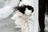 a bold black and white wedding bouquet of white roses and orchids, some blooming branches, black blooms and feathers