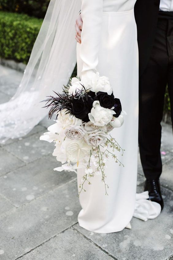 a bold black and white wedding bouquet of white roses and orchids, some blooming branches, black blooms and feathers
