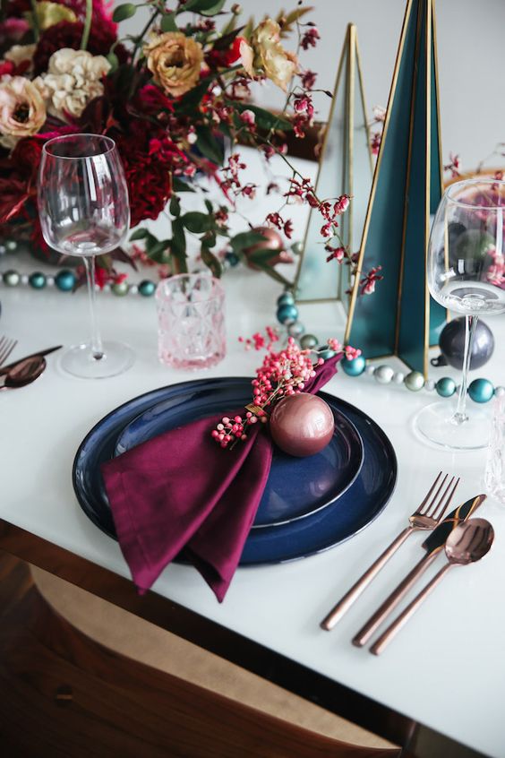 a bold floral centerpiece paired up with cool cardboard Christmas trees and an ornament garland are a very nice combo