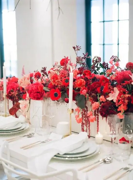 a bold red floral centerpiece - a box with bright blooms and leaves and some neutral candles for a chic look