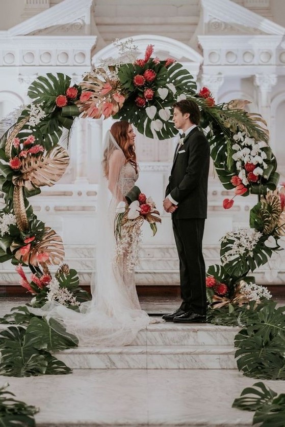 a bold round wedding arch with fronds, gilded fronds, white and pink blooms for a refined tropical wedding