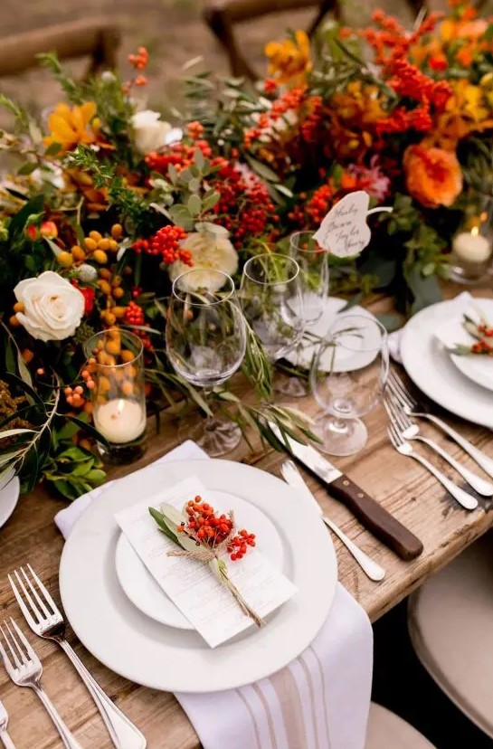 a bright harvest wedding reception with bold blooms, berries and greenery, with neutral porcelain and linens, with berries on each place setting