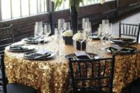 a bright wedding tablescape with a gold sequin tablecloth, black plates, white blooms in a black vase