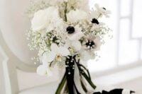 a chic black and white wedding bouquet of white orchids, roses and anemones, baby’s breath, some black and white ribbons