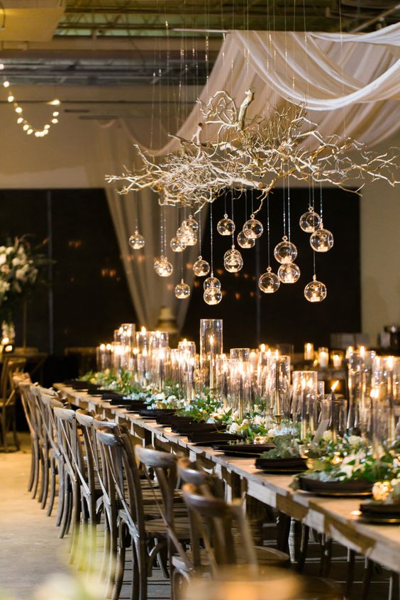 a cool NYE wedding tablescape with a gilded branch with bubbles hanging down, tall and thin candles and black plates