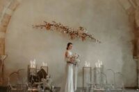 a fantastic minimalist wedding space with a blooming branch arrangement and candles for the altar plus ghost chairs lined up with candles