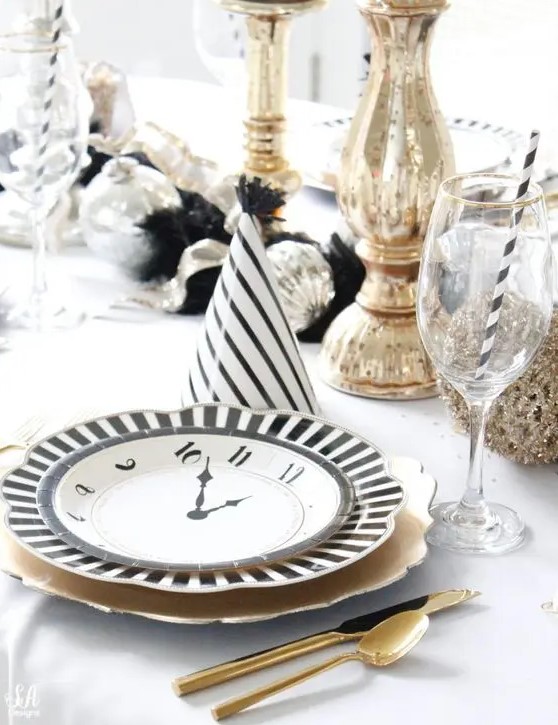 a glam NYE wedding table setting with gold chargers and cutlery, tall candleholders and silver ornaments is a cool shiny idea