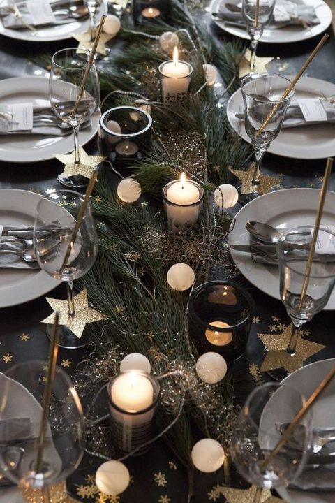 a homey NYE wedding tablescape with evergreens, a lights garland, candles, gold stars