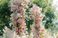 a jaw-dropping wedding arch with pink, orange and white blooms, dyed baby’s breath and pampas grass is gorgeous for a garden wedding
