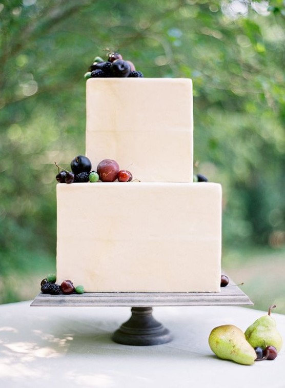 a laconic neutral square wedding cake topped with fresh fruits and berries for a modern wedding