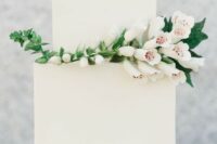 a laconic white square wedding cake decorated with a branch of white blooms is a stylish idea for a minimalist wedding