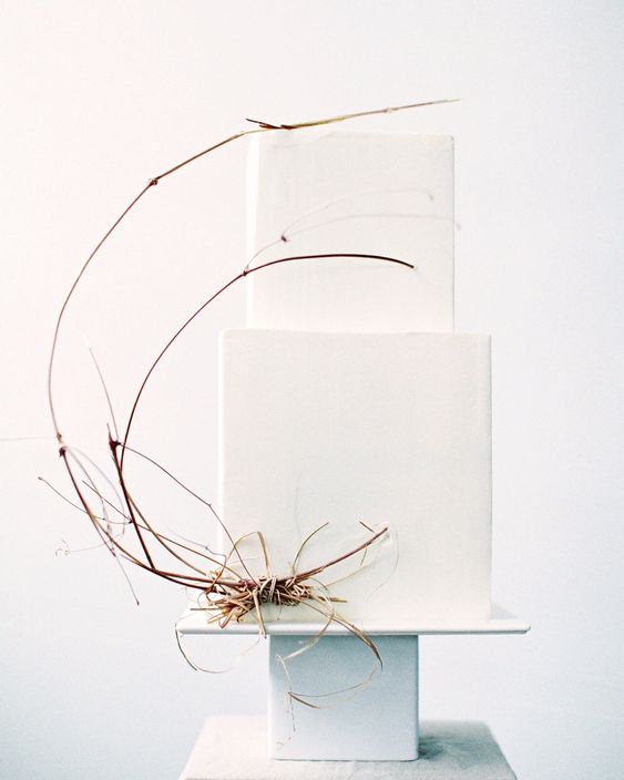 a minimalist beach square white wedding cake decorated with a bit of twigs is a beautiful piece that looks unusual