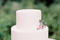 a minimalist plain white wedding cake topped with some berries for a modern natural or minimalist wedding