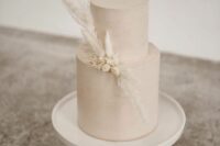 a minimalist tan wedding cake topped with a bit of dried fresh blooms and grass in white is a beautiful idea