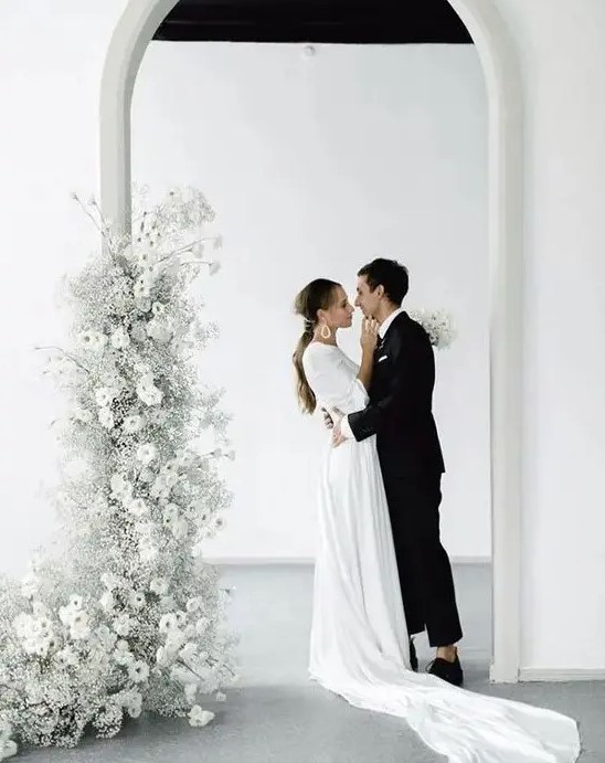 a minimalist wedding altar of a doorway decorated with ethereal white blooms, blooming branches and baby's breath is a gorgeous solution