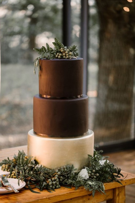 a minimalist wedding cake in black and pearly, with fresh greenery and berries on top