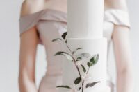 a minimalist white wedding cake decorated with a single blooming branch is a chic and stylish idea to rock for a spring wedding